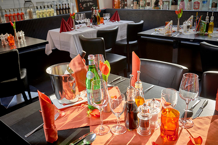 Gedeckter Tisch in Orange mit Tulpen - Wir richten gerne Ihre Feier aus!